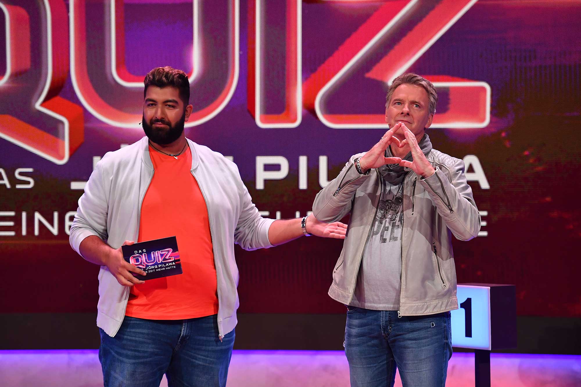 Faisal Kawusi mit Jörg Pilawa vor der Quizwand